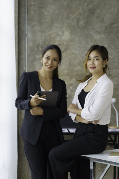 两个漂亮的亚洲女商人站在办公室用平板电脑讨论各部门的重要信息任务。图片下载