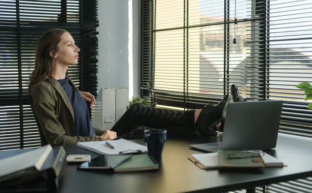 平静的女工享受她的早晨，透过窗户看。图片下载