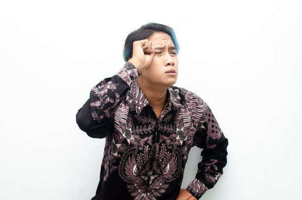 悲伤哭泣的迷人的亚洲男子穿着蜡染衬衫哭手势和擦眼泪图片下载