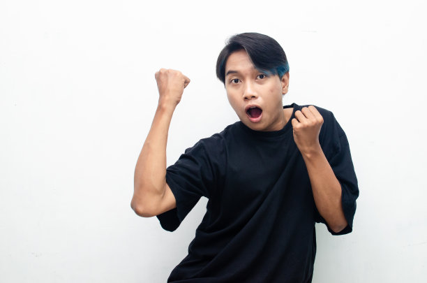 一个亚洲男人，一头浓密的头发，开心地跳舞，用手势举起拳头庆祝好消息，孤立在白色背景上。人，欢乐，乐趣和幸福的概念。图片下载