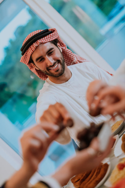 现代多民族穆斯林家庭在家里享用开斋晚餐时分享一碗椰枣图片下载