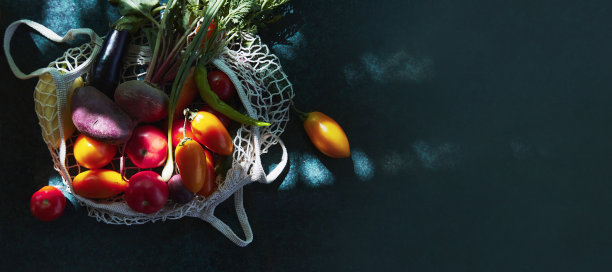 新鲜蔬菜-黄色的西红柿，茄子，洋葱，甜菜根在生态购物袋在时尚硬阴影与反射背景。生态问题。副本的空间。特宽横幅图片下载