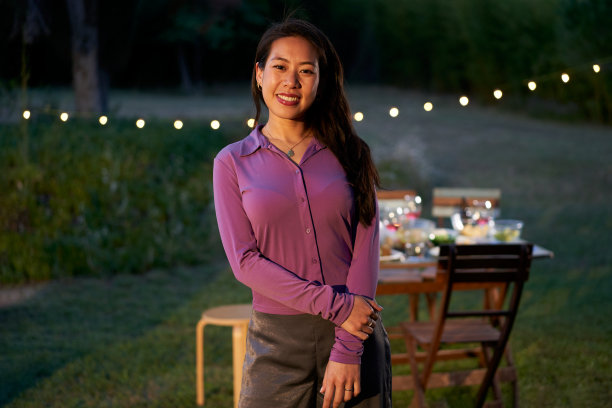 一个亚洲女服务员看着镜头的照片。微笑着的中国女服务员站在桌子前的露台上。图片下载