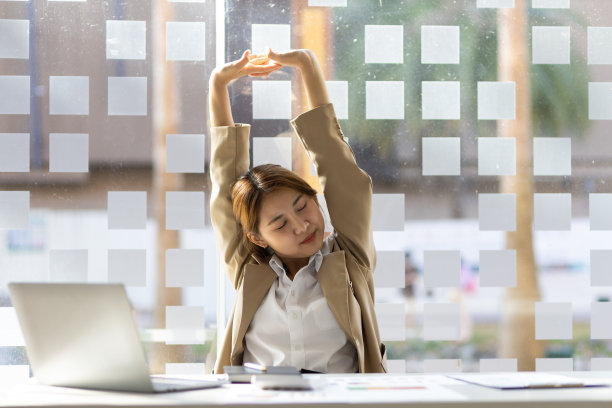 在办公室工作的女商人会在工作休息时伸伸懒腰放松一下。图片下载
