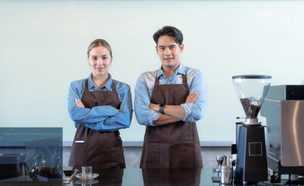 咖啡厅工作人员站在柜台前，对着镜头微笑。图片下载