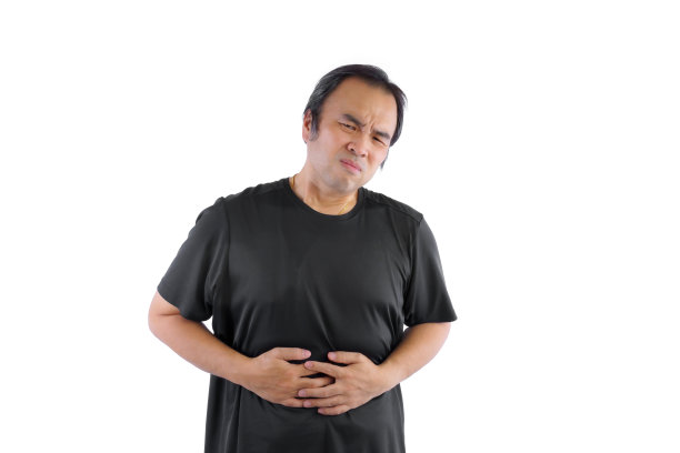 穿着黑色t恤的亚洲男子，他做着痛苦的表情，把手放在肚子上，因为他生病了，胃疼。图片下载