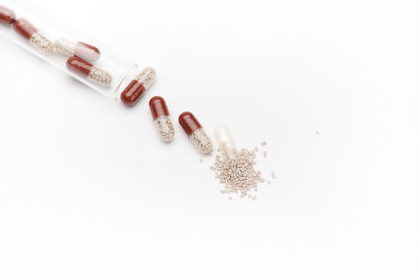 仍然生活。从上方看，肠胶囊从凝胶状半透明胶囊中溢出，散落在白色背景上图片下载