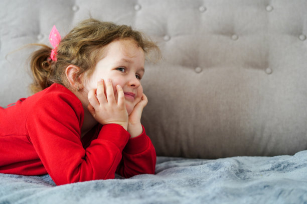 搞笑的小女孩躺在家里的床上，快乐的童年图片下载