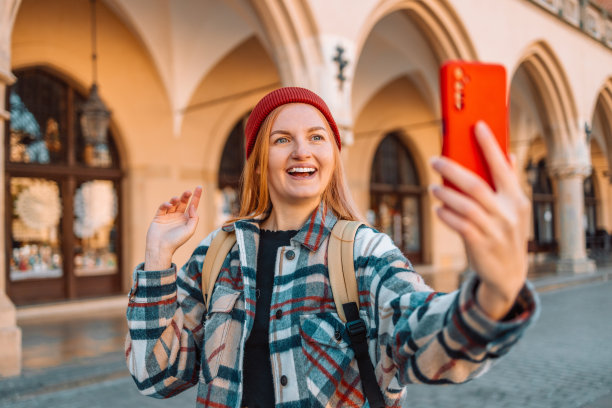 波兰克拉科夫集市广场上，20多岁的旅行女性用智能手机开心地自拍。环游欧洲图片下载