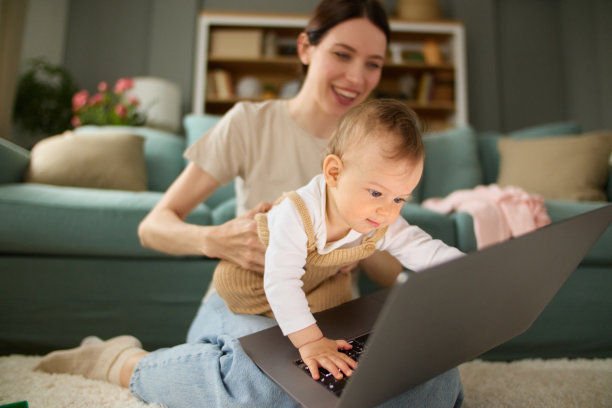 可爱的小男孩和他的妈妈坐在客厅的地板上使用笔记本电脑图片下载