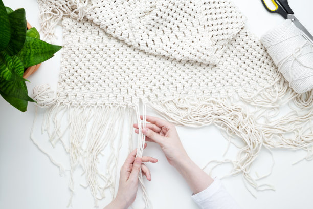 创意爱好手工编织的家庭装饰。女孩在编织流苏。妇女编织编织板的家庭装饰。平躺，俯视图图片下载