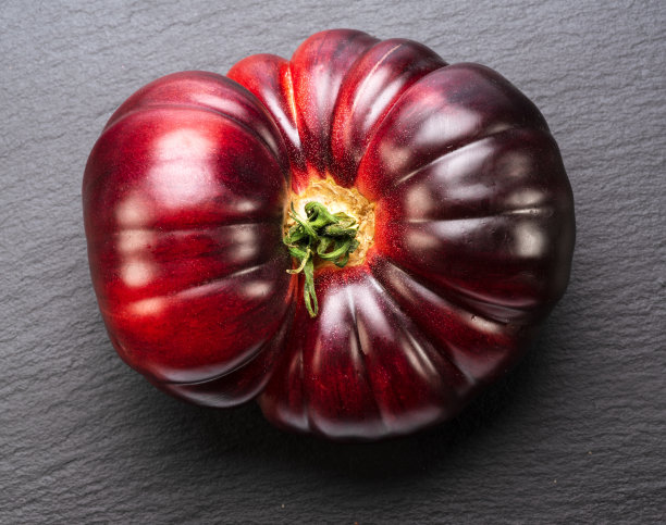 成熟的黑色或紫色番茄在灰色石板石背景。前视图。图片下载