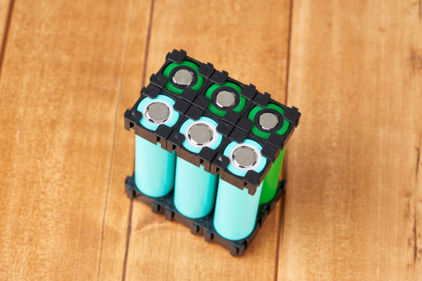 锂电池包在黑色塑料支架上的木桌。图片下载