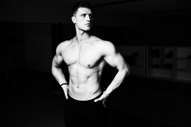 一个年轻的健美男子展示他训练有素的身体的肖像-肌肉发达的健美运动员健身模特在锻炼后摆姿势图片下载