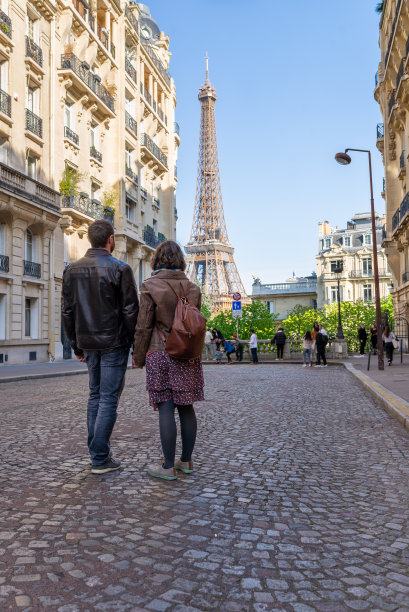 一对异性恋夫妇在巴黎度假时手拉手看着埃菲尔铁塔的后视图。图片下载