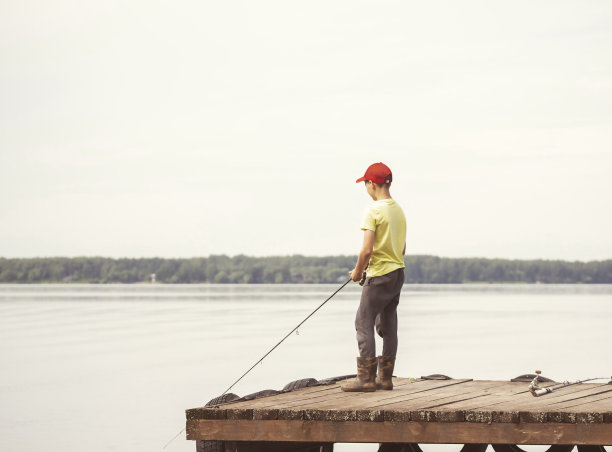 一个少年在河里钓鱼。休闲概念，夏季，心理健康。图片下载