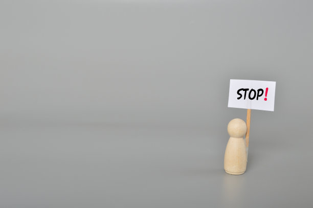 是时候放弃了。一个手持停止标志的木制人物的特写图像，暗示是时候停止并结束诉讼了。图片下载