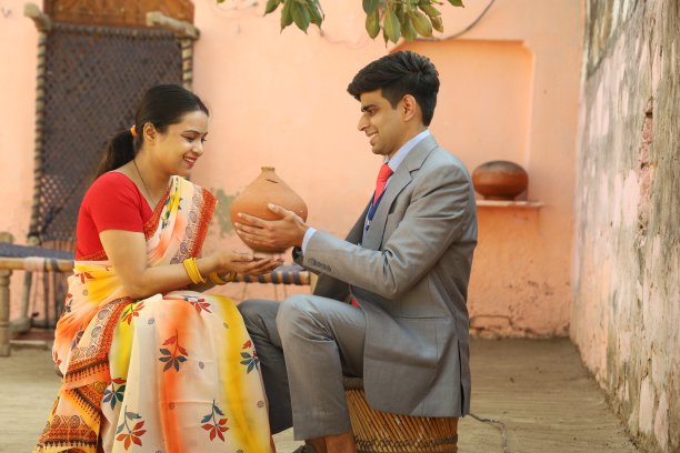 快乐的印度妇女穿着纱丽服向银行家贷款。手里拿着储蓄罐。图片下载