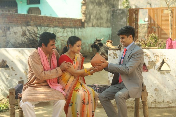 快乐的印度农民和村民夫妇从银行家那里贷款。丈夫和妻子从银行家手里拿着扑满。图片下载