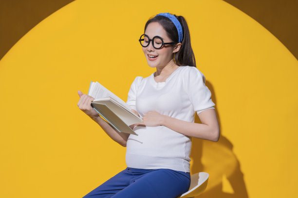 快乐妈妈怀孕的亚洲女人坐着放松阅读婴儿书籍研究带着欢快的积极情绪，平静的亚洲女人享受阅读爱好放松为她的婴儿怀孕的工作室拍摄图片下载