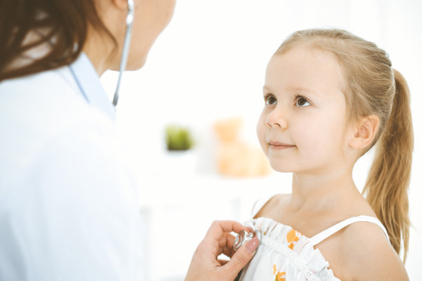 医生用听诊器检查一个小女孩。在例行体检中开心微笑的孩子。医学和保健概念图片下载