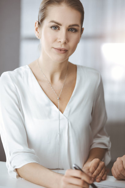 女商人坐在阳光明媚的办公室里看着镜头图片下载