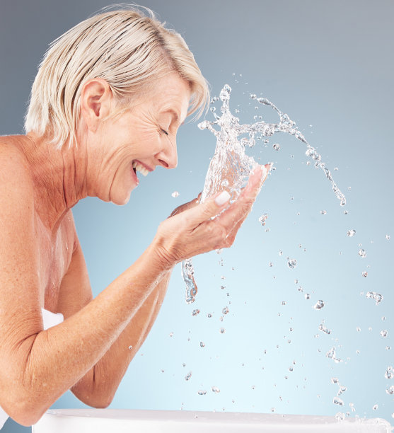 资深女士，清洁面部和水溅在工作室背景美容，健康和淋浴。快乐模型，面部护肤滴剂和浴室洗涤，美观，化妆品和健康的身体图片下载