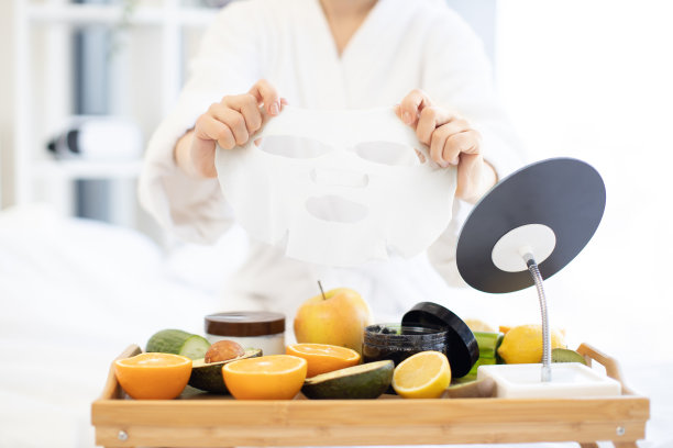 女士将面膜放在托盘上的水果和化妆品上图片下载