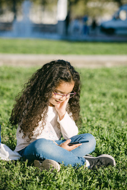 小女孩在公园里用眼镜和手机的照片图片下载