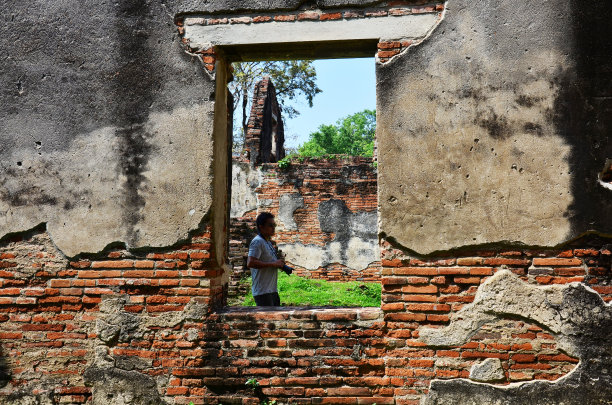 泰国男子摄影师旅行者，人们旅游参观和使用数码相机拍摄照片，在罗布武里，罗布武里市的大使官邸或Wichayen住宅古代遗迹图片下载