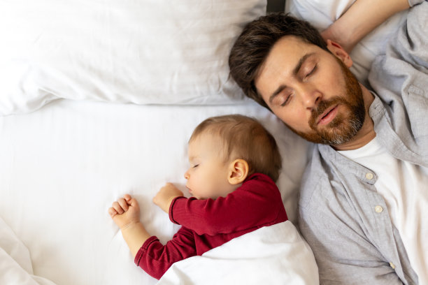 爸爸和小婴儿一起睡在床上。图片下载