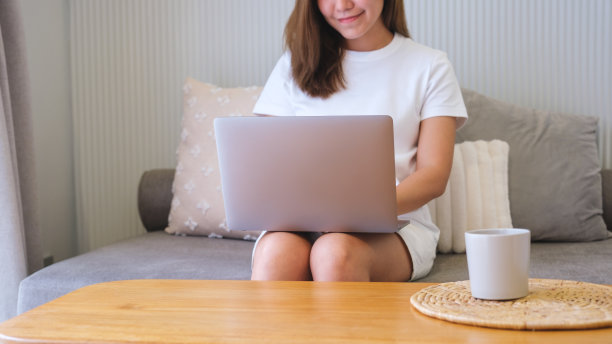 一个年轻女子在家里用笔记本电脑工作的特写图片下载