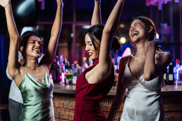 亚洲美女们在酒吧餐厅里欢聚一堂。有吸引力的年轻女孩朋友感到快乐和放松，在夜总会举行聚会，喝酒庆祝活动。图片下载