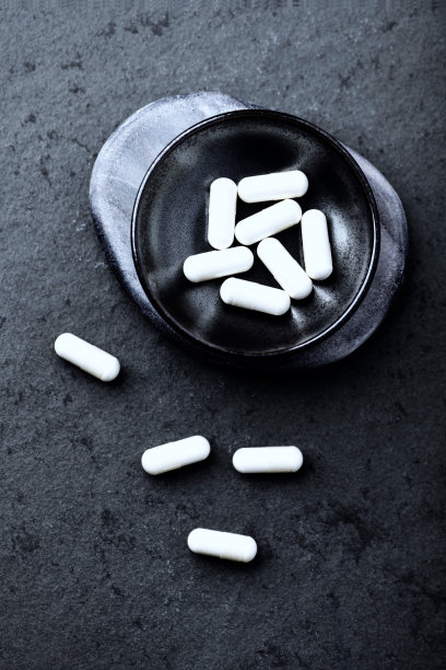 运动补充剂(肌酸胶囊)暗石背景。前视图。关闭了。副本的空间。图片下载