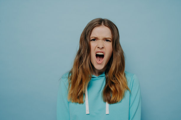 漂亮的十几岁的女孩表达愤怒的怀疑，在蓝色的背景下摆出孤立的姿势图片下载