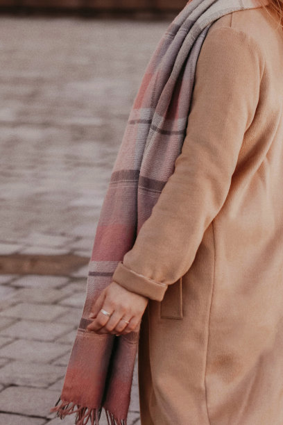 女性形象穿着米色的秋色保暖长大衣，配着格子围巾。图片下载