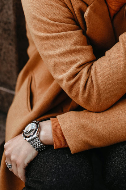 细节的橙色温暖舒适的女性大衣和手与配件。户外肖像。图片下载