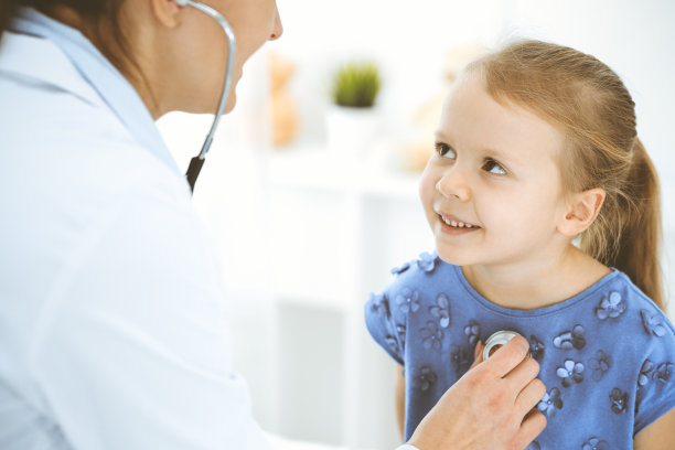 医生用听诊器检查一个小女孩。在例行体检中开心微笑的孩子。医学和保健概念图片下载