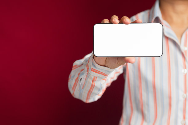 手持智能手机的特写，在红色背景下站着，空白的复制空间屏幕显示短信或信息图片下载