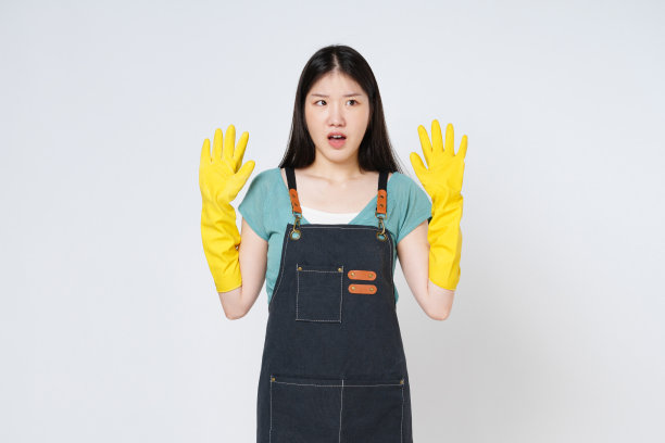 年轻女子的肖像举起双臂，戴着黄色橡胶手套，张开嘴，孤立在白色背景上。图片下载