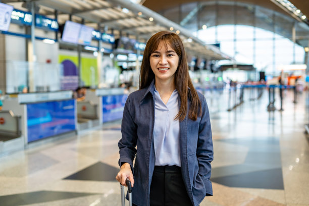 积极的女人在机场拿着行李。图片下载
