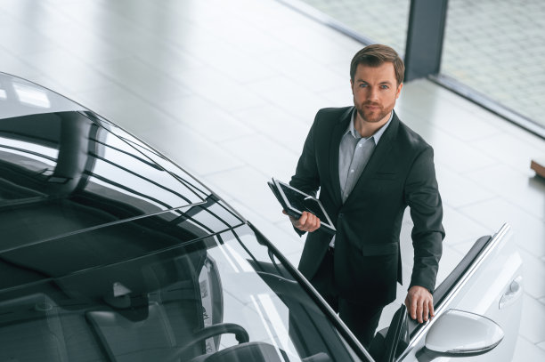 俯视图，平板电脑。穿着黑色西装的男子在汽车经销店的室内图片下载