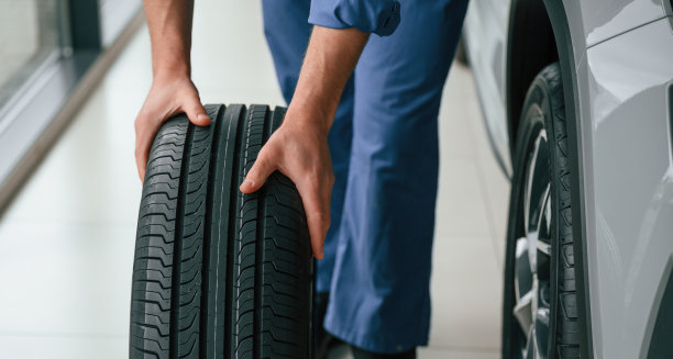 前视图，移动轮胎。穿蓝制服的人在汽车维修处工作图片下载