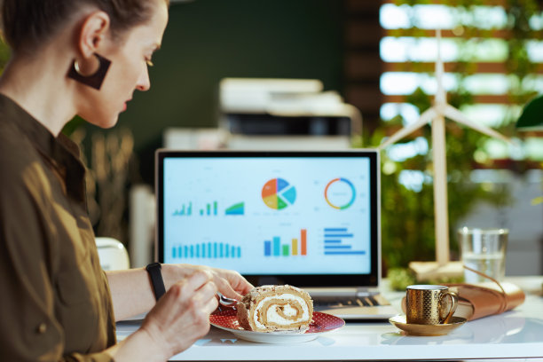 从背后看，现代女性拿着笔记本电脑和一块蛋糕图片下载