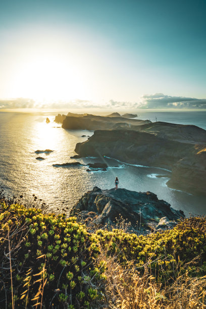 在日出时，女人在陡峭的悬崖上欣赏海景，沿着马德拉海岸崎岖的山麓欣赏全景。Ponta do Bode，马德拉岛，葡萄牙，欧洲。图片下载
