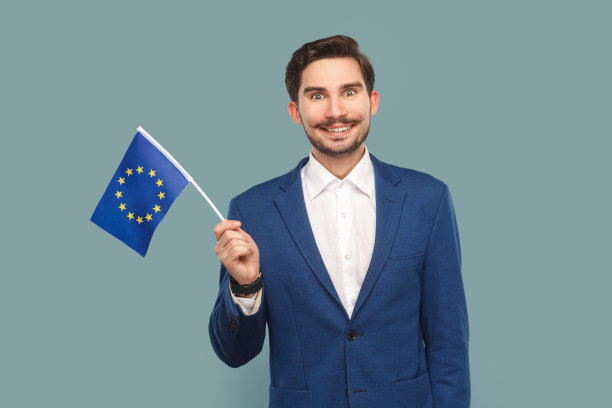 微笑着的快乐帅哥站在那里挥舞着欧盟旗帜，表达着幸福。图片下载