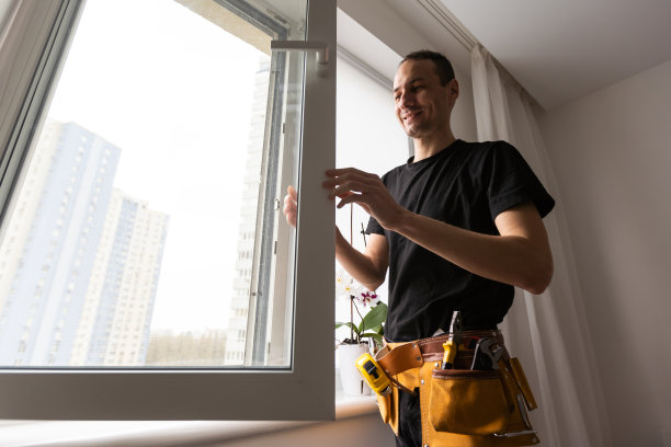 在建筑工地安装窗户的男性工业建筑工人图片下载