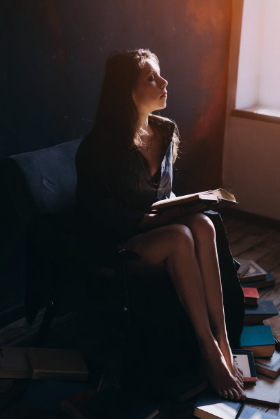 一个放松的女人坐在满屋子的书里看书图片下载
