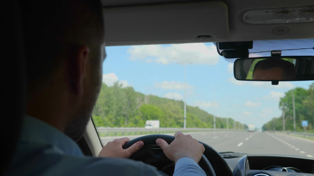 后面的白人年轻司机开着一辆车，看着道路。穿着衬衫的英俊成年商人驾驶他的汽车的特写。交通、出差概念图片下载