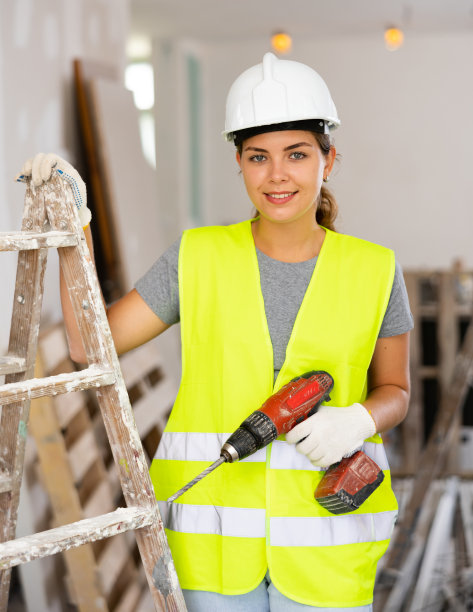微笑的女建筑工人拿着钻头，在公寓里修理工程图片下载